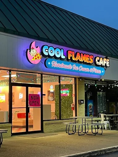 Exterior view of Cool Flames Cafe storefront showcasing illuminated business signage, patio seating, and ice cream parlor entrance.