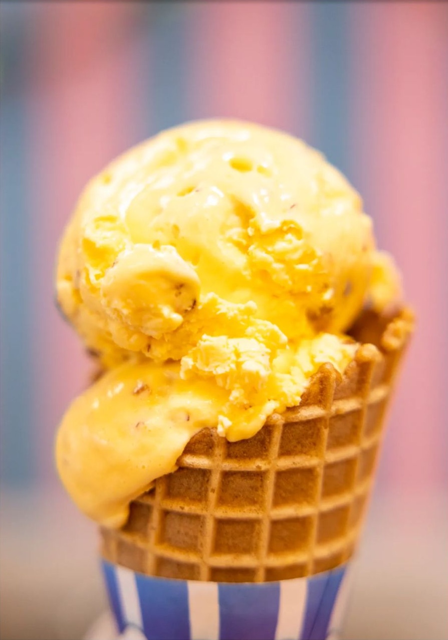 Fresh handmade mango ice cream scoop in a crispy waffle cone at Cool Flames Cafe.