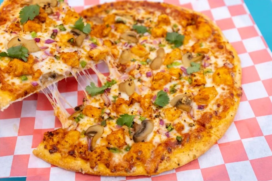 Freshly baked handmade chicken pizza with cheese pull, sliced mushrooms, onions, and cilantro toppings served at Cool Flames Cafe.